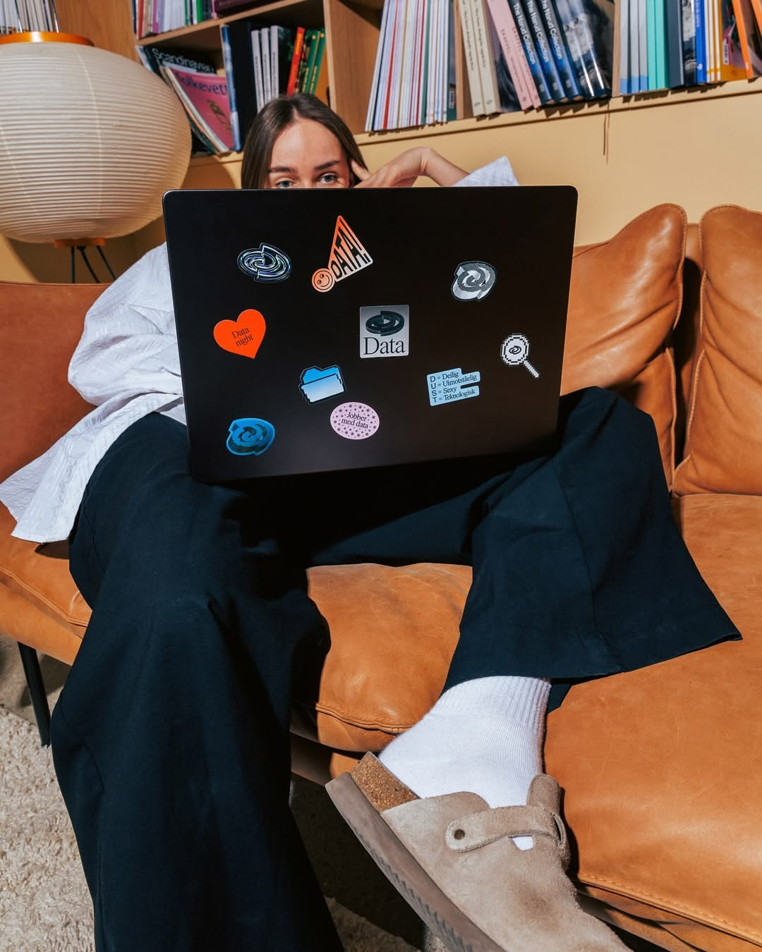 Editora com laptop coberto de stickers — vida real de quem vive em set e edição
